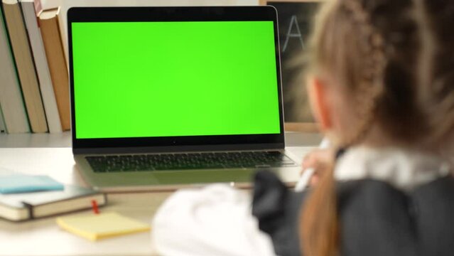 A cute little girl using with a laptop. Green screen for replacement