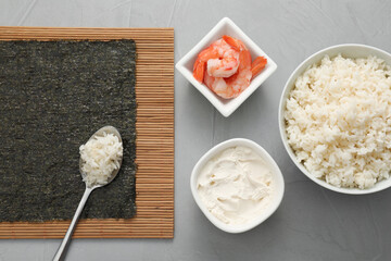 Cooking sushi. Nori, spoon with rice and other ingredients on grey textured table, flat lay