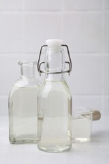 Vinegar in glass bottles and saucepan on light table
