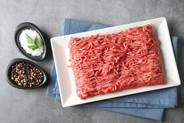 Raw ground meat and spices on grey table, top view