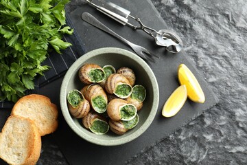 Delicious cooked snails served on grey textured table, flat lay