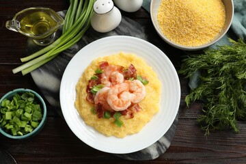 Plate with fresh tasty shrimps, bacon, grits and green onion on dark wooden table, flat lay
