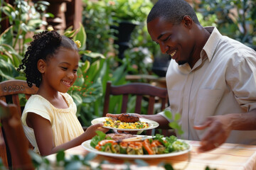 African American man serving a plate of food to a young girl seated at a table. Enjoying grilled cuisine outdoors during a family garden gathering. - Powered by Adobe