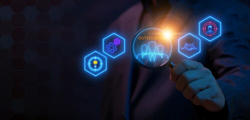 Outsourcing concept. Human resources and global recruitment for business working and company. Businessman holding magnifying glass to show outsourcing icon on virtual screen.