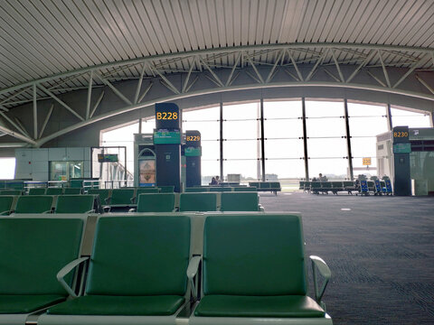 In the departure hall of Beijing Airport, people are waiting for flights on green seats to their destinations.