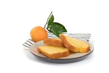 slices of orange loaf cake on a plate with a leafy orange in the background isolated on white