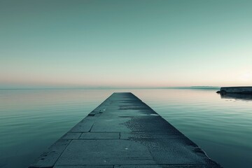 A concrete dock jutting out into a calm lake at sunrise