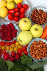 Apples, lemons, bananas, berries, carrots, leek, tomatoes, radishes, spinach and various nuts on white background. Healthy seasonal fruit and vegetable. Selective focus.