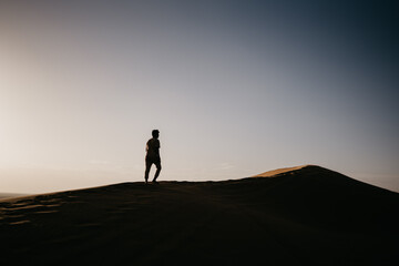Fototapeta na wymiar silhouette of a person walking on the sand