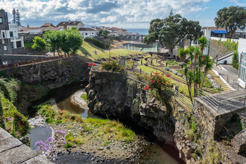 Stream between walls in the Ribeira Grande public garden with aqueduct and sea in the background, São Miguel - Azores PORTUGAL
