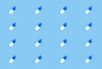 Seamless repetitive two-piece hard starch capsule pills on blue background. Health concept.
