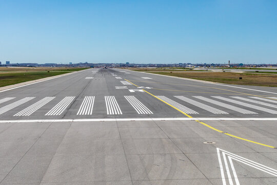 Looking down at airport runway 24 from inside an airplane about to take off on a clear day showing tire marks in the distance