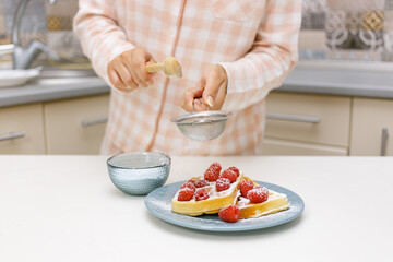 A young girl is cooking waffles.
