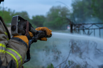 Fireman extinguishing a fire on a field. Cropped image. Men at work concept