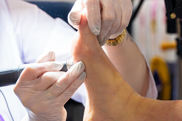 A professional cosmetologist makes a hardware pedicure on a woman leg in the cabin. Close -up the...