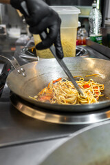 chef hand cooking Noodle with vegetables on restaurant kitchen