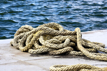 A pile of rope on a dock at the water edge