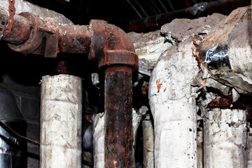 old torn asbestos insulation on rusty pipes
