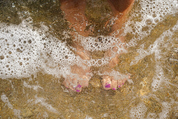 A female feet are in the water with bubbles surrounding them