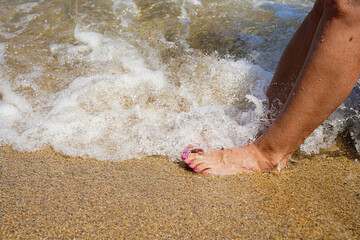female feet splashing in the ocean water