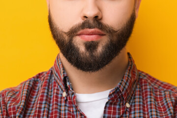 Handsome man with mustache on yellow background, closeup