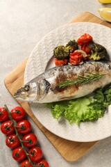 Delicious baked fish and vegetables on light grey table, top view