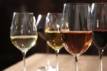 Different tasty wines in glasses against blurred background, closeup