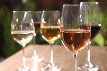 Different tasty wines in glasses against blurred background, closeup