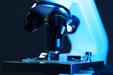 Microscope with glass slide on dark blue background, closeup