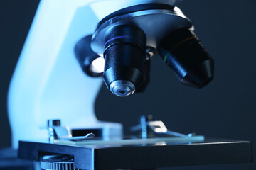 Microscope with glass slide on dark blue background, closeup