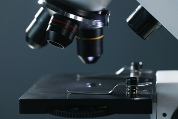Microscope with glass slide on dark background, closeup