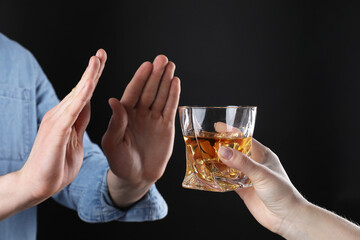 Alcohol addiction. Man refusing glass of whiskey on dark background, closeup