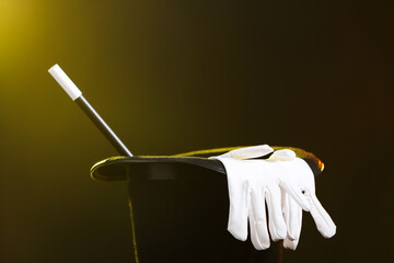 Magician's hat, wand and gloves on dark background, closeup