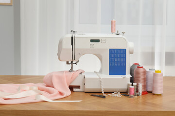 Sewing machine with fabric and craft accessories on wooden table indoors
