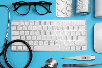 Flat lay composition with keyboard and medical supplies on light blue background