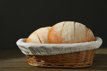 Wicker basket with fresh bread on wooden table