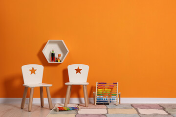 Beautiful children's room with bright orange wall and furniture, space for text. Interior design