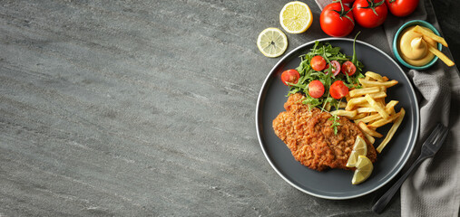 Tasty schnitzels served on grey table, flat lay. Banner design with space for text