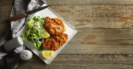 Tasty schnitzels served on wooden table, flat lay. Banner design with space for text