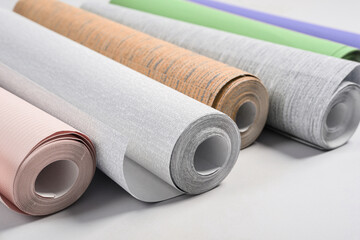 Different wallpaper rolls on light grey background, closeup