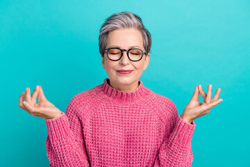 Photo of peaceful positive woman with short hair dressed pink sweater in glasses relaxing meditating isolated on teal color background