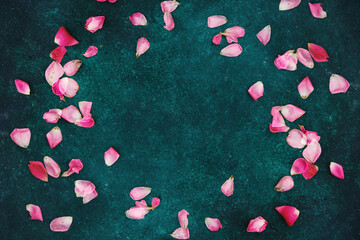 Pink rose petals on elegant green texture background with copy space.