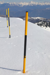 posts stuck in the yellow and black snow to mark the edge of the road after the snowfall in the mountains
