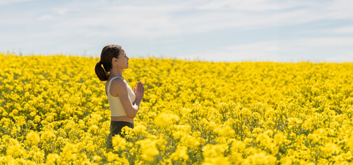 Woman breathing fresh air in a yellow field and practicing yoga meditation
