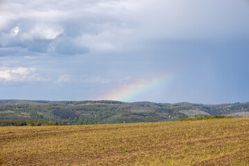 A rainbow is seen in the sky above a field