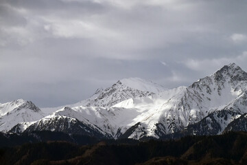 Obraz premium Snow covered mountains in cloudy weather, Tian Shan, large system of mountain ranges in Central Asia