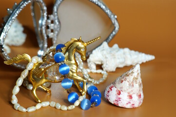 A statuette of a metal unicorn decorated with decorative glass and jewelry.