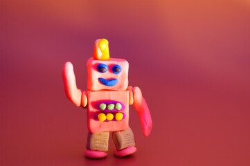 A funny plasticine robot dances on a colored background.