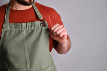 Man in a red T-shirt with an apron on a gray background