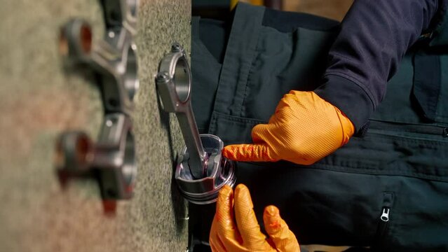 vertical video close-up At a service station on the table young engine repairman assembles a new piston part
